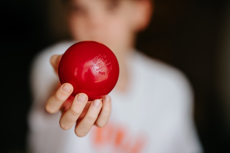 Gyerek kezében piros műanyag labda